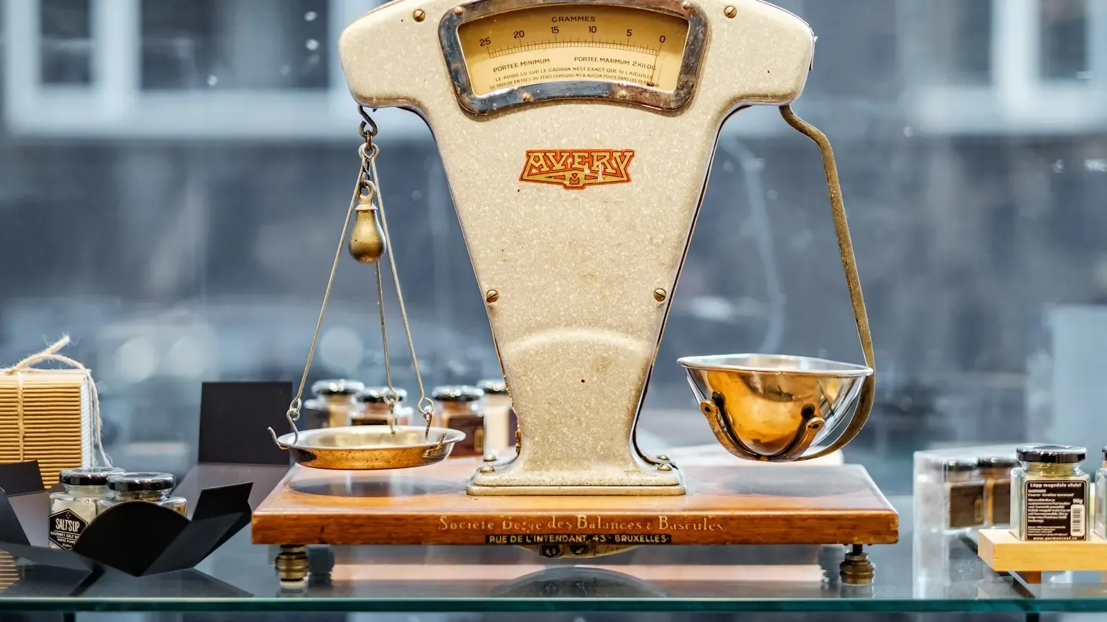 A vintage cream-colored balance scale with a brass weighing pan on a shop counter